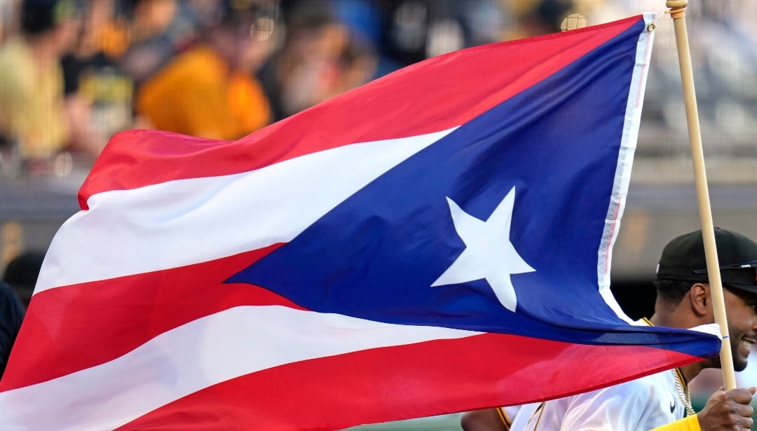 Pittsburgh Pirates right fielder Joshua Palacios carries the flag of Puerto Rico in honor of Roberto Clemente Day as he takes the field for the team's baseball game against the New York Yankees in Pittsburgh, Friday, Sept. 15, 2023. (AP Photo/Gene J. Puskar)