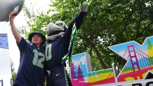 A fan takes a selfie with Blitz the Seahawk next to a Lombardi Trophy and a Super Bowl LX sign during the Seattle Seahawks NFL football team's training camp, Saturday, July 25, 2026, in Renton, Wash. (AP Photo/Lindsey Wasson)